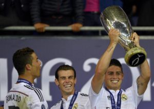 Real Madrid's James Rodriguez (R) raises up the trophy beside team mates Cristiano Ronaldo (L) and Gareth Bale after winning the UEFA Super Cup final against Sevilla at Cardiff City stadium, Wales, August 12, 2014.  REUTERS/Rebecca Naden (BRITAIN  - Tags: SPORT SOCCER)